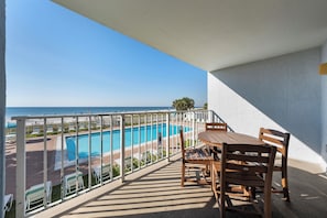En balkon med udsigt over en swimmingpool og havet.