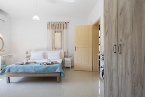 A bedroom with a bed, bedside tables, a wardrobe, and a door. - Villa 'Leondis' with Mountain View, Wi-Fi and Air Conditioning (Μελιδόνι)