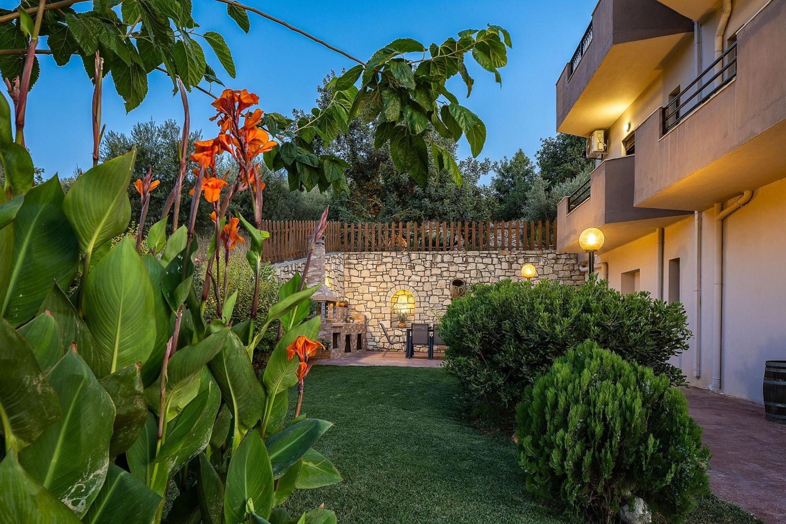 A courtyard with a stone wall, a wooden fence, and a seating area with a table and chairs.