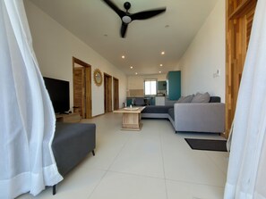 Una sala de estar moderna con un sofá, televisor y ventilador de techo.