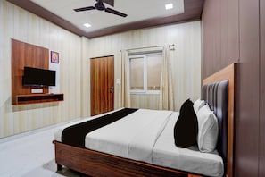 A bedroom with a bed, a television mounted on the wall, a ceiling fan, and a window with curtains. - Hotel O Brijbhav Vrindavan The Spiritual (Vrindavan)