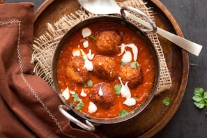 A bowl of meatballs in tomato sauce with dollops of cream and parsley garnish. - Hotel O Stay Inn Maharani Peta (Visakhapatnam)