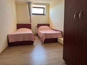 A small room with two beds, a wooden wardrobe, and a window with curtains. - Spacious Garden-Level Apartment with Ararat Views (Kotayk)