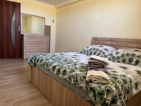 Un dormitori amb llit i armari de fusta, i una porta.