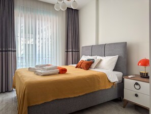 Una habitación de hotel con una cama, una mesita de noche, una lámpara y cortinas.