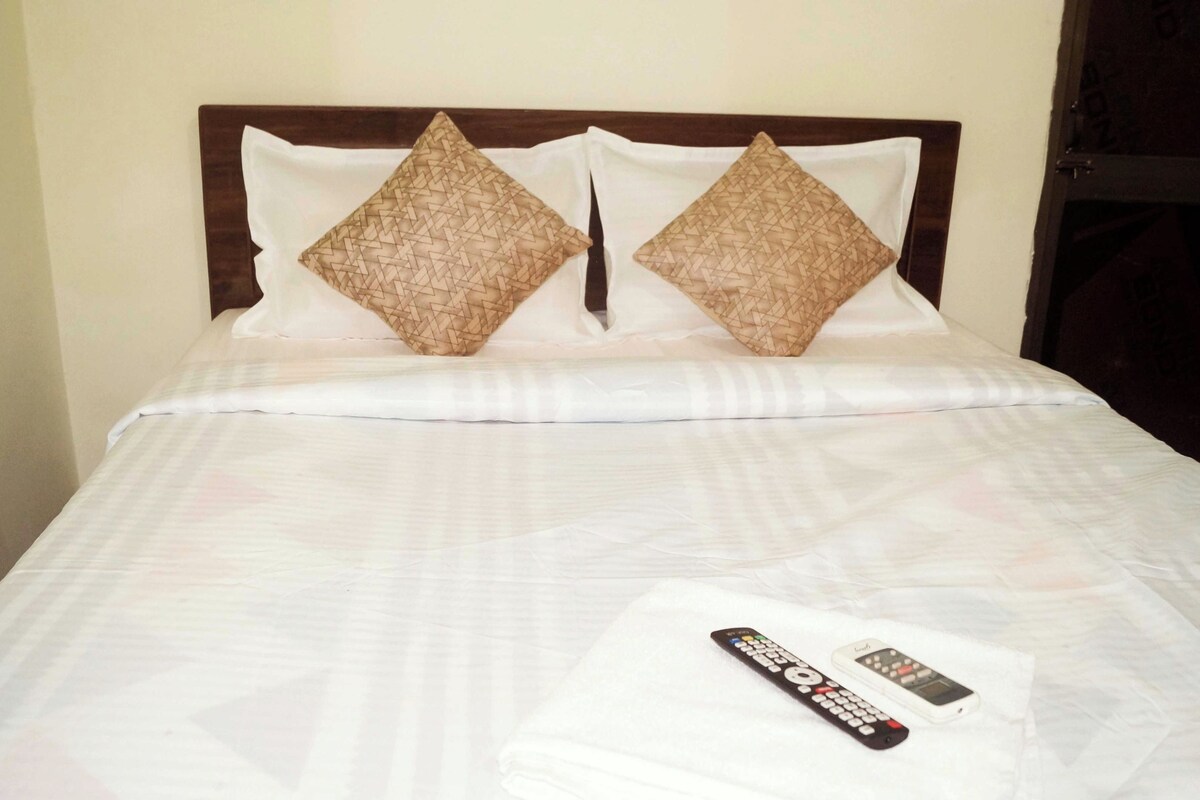 A neatly made bed with a white bedspread and two decorative pillows.