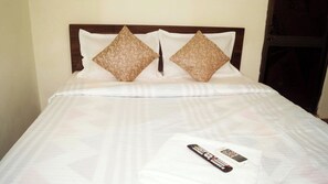 A neatly made bed with a white bedspread and two decorative pillows. - Hotel O Mishra Suites (Varanasi)
