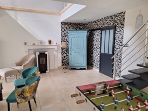 Una habitación con sofá, pared con diseño, armario y mesa de fútbol.