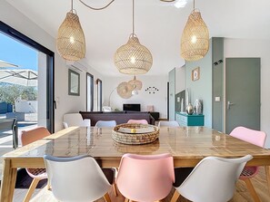 A modern dining area with a large table, chairs, and hanging pendant lights. - New Listing (Bédoin)