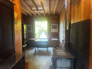 Un intérieur en bois avec une cheminée, une table et une fenêtre donnant sur les arbres.