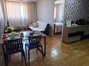 Un espacio habitable compacto con comedor, kitchenette y dormitorio.