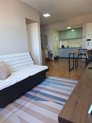 Una sala moderna con un sofá, una mesa de comedor y una cocina al fondo.