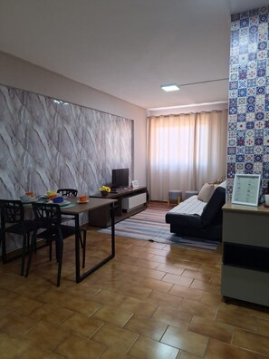 A living room with a dining area, a sofa, a TV, and a patterned wall. - New Listing (Rondonópolis)