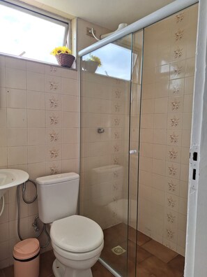 Un baño con inodoro, lavabo y cabina de ducha.