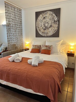 Een hotelkamer met een groot bed, een decoratief wandobject en een schilderij.