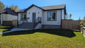 Ein eingeschossiges Haus mit Eingangsbereich, einer Treppe und einem umzäunten Garten.