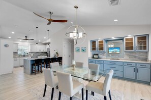 A modern kitchen with a central island, a dining area with a glass table, and a large window with a view. - Outdoor Oasis ~ 3-bedroom house in marvelous Key Colony Beach with pool and dock (Key Colony Beach)