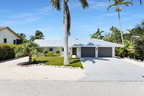 A modern two-story house with a garage, surrounded by tropical vegetation. - Outdoor Oasis ~ 3-bedroom house in marvelous Key Colony Beach with pool and dock (Key Colony Beach)