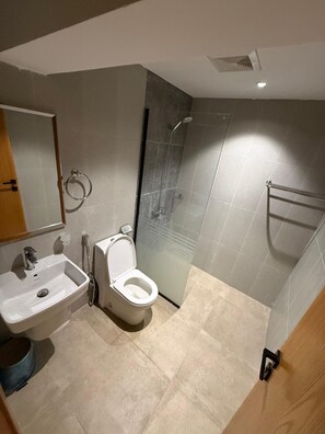 Un baño moderno con lavamanos, inodoro y cabina de ducha de vidrio.