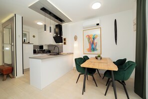 A modern kitchen with a central island, pendant lighting, and a dining area with green chairs. - Apartment Simba with Private Heated Pool & Jacuzzi (Novalja)