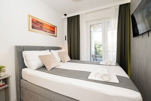 Een moderne hotelkamer met een groot bed, een flatscreen televisie en een raam met gordijnen.