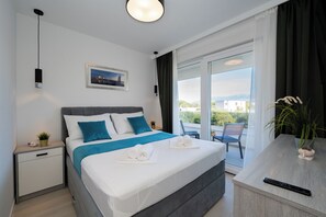 Quarto de hotel moderno com cama, mesa de cabeceira e vista para o exterior.