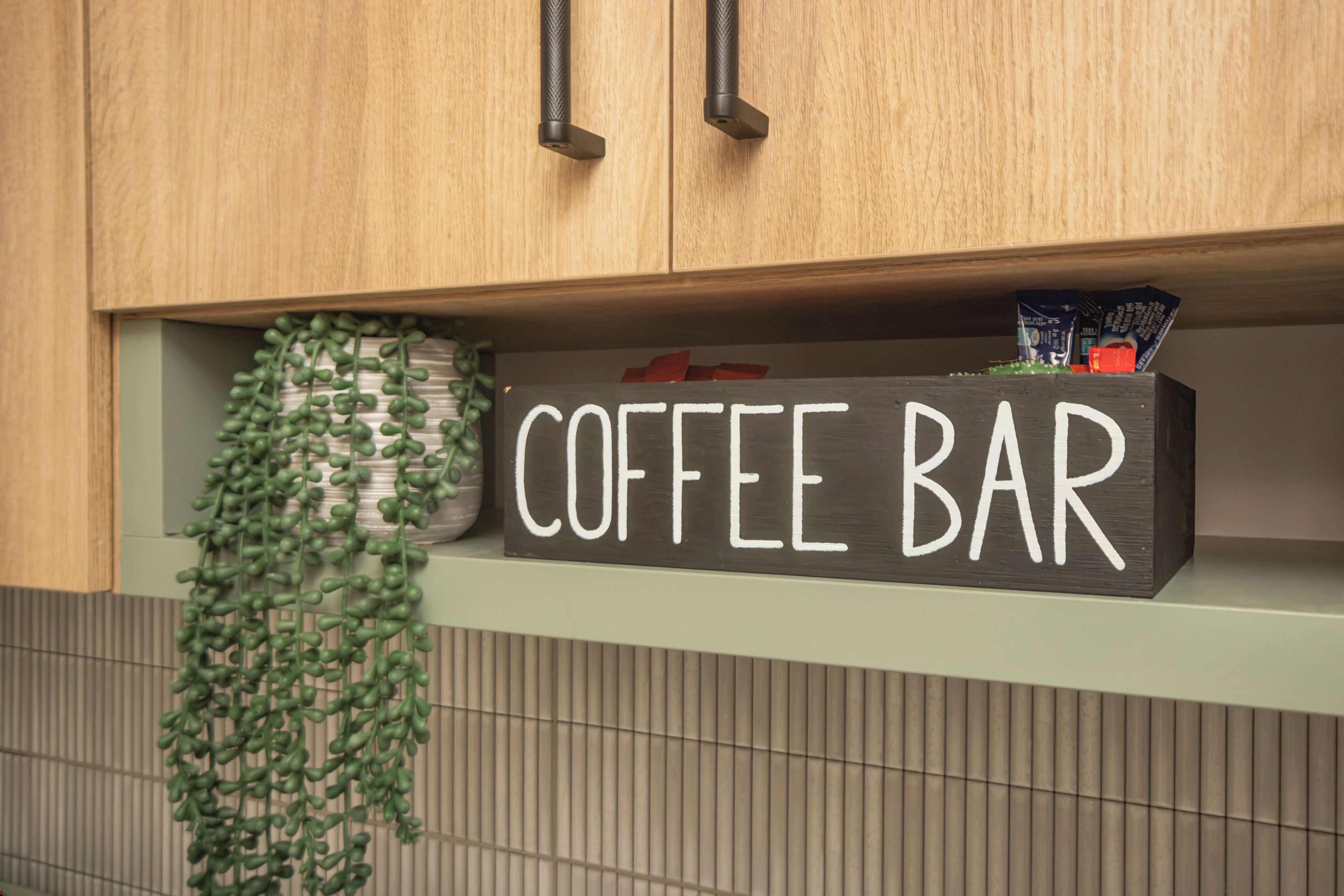 Uma área de cozinha com uma placa na prateleira que diz 'COFFEE BAR'.
