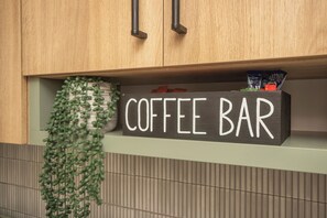 Un coin cuisine avec une étiquette indiquant « BAR À CAFÉ » sur une étagère.