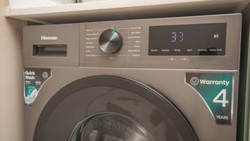 A front view of a Hisense washing machine with a digital display and a warranty sticker.