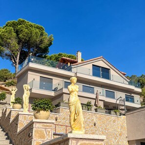 A multi-story building with a stone facade, balconies, and outdoor statues.