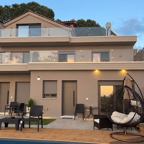 Ein zweistöckiges Gebäude mit Balkon, Sitzbereich im Freien und Pool.