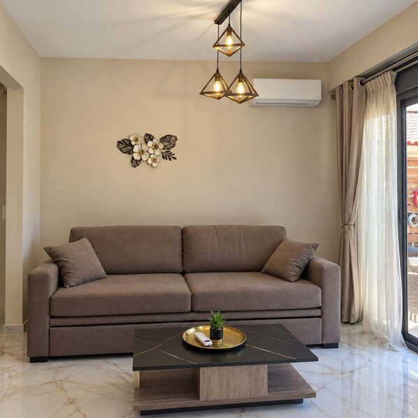 A modern living room with a sofa, a coffee table, pendant lights, and a decorative wall piece.