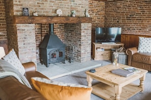 Una sala de estar acogedora con chimenea de ladrillo, televisión y asientos cómodos.