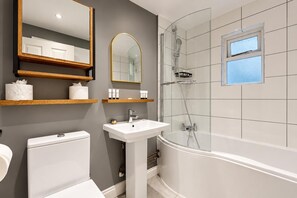 Une salle de bain avec des toilettes, un lavabo, une douche et une fenêtre.