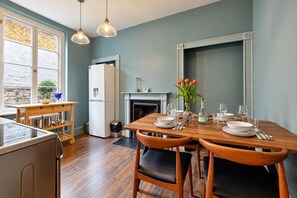 Une cuisine moderne avec une table à manger pour quatre personnes, un réfrigérateur et une cheminée.