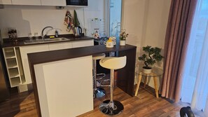 Een compacte keuken met een bar, een spoelbak en een kleine eettafel.