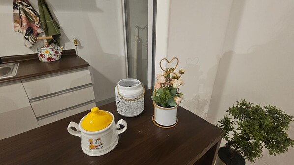 Een keukentrap met een gele pot, een witte keramieken container en een vaas met bloemen.