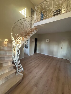 Un intérieur spacieux avec un escalier en bois et un balcon au deuxième étage.