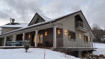 Et toetagers hus med en overdækket veranda, en balkon og et sneklædt landskab.