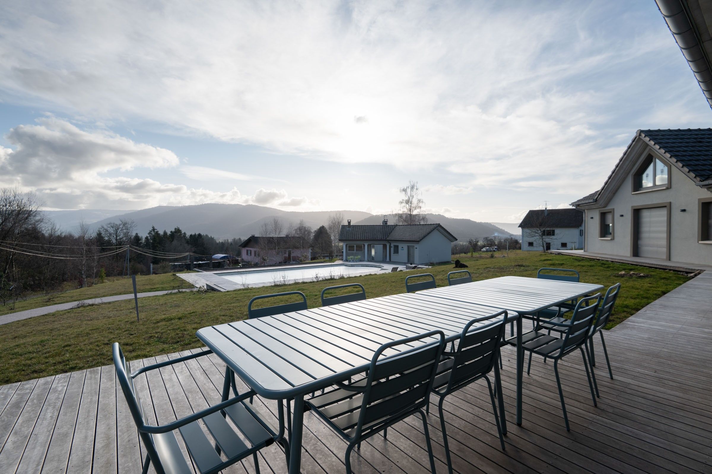 Eine Terrasse mit Tisch und Stühlen mit Blick auf einen Swimmingpool und eine Berglandschaft.