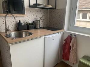 Eine kleine Küche mit Spüle, Mikrowelle und Kühlschrank.