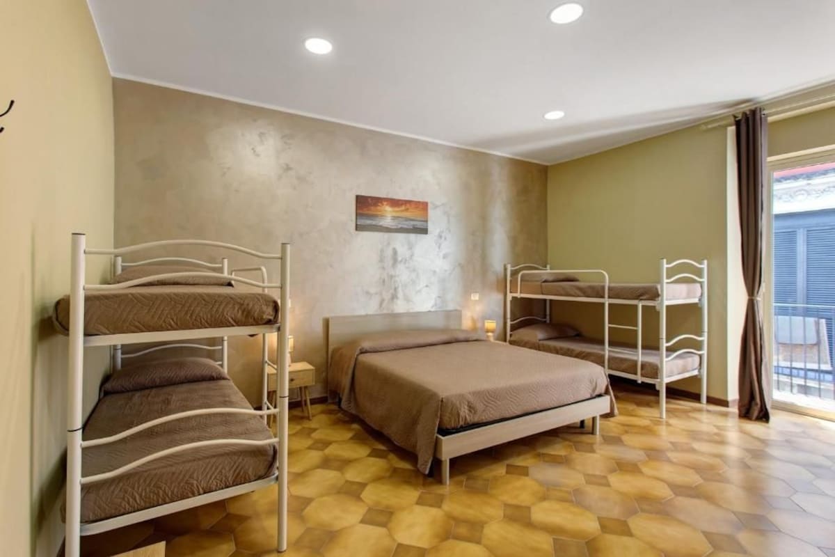 A room with bunk beds, a single bed, and a painting on the wall.