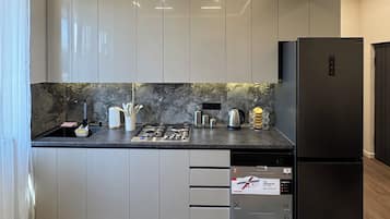 Una cucina moderna con mobili grigi, un frigorifero nero e uno schienale in marmo.