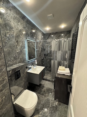 A modern bathroom with a marble floor, a large mirror, a shower with a glass enclosure, and a vanity with a sink and towel stack. - Modern New Apartment- Metro at your door (Երևան)