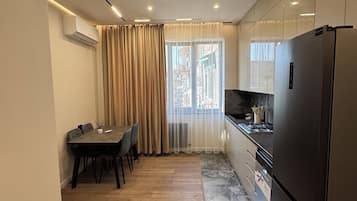 Een moderne keuken met een eethoek, voorzien van een grote koelkast, een fornuis en een eettafel met stoelen.