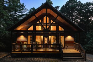 Une cabane en rondins dotée d’un porche et d’un escalier menant à l’entrée.