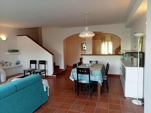 Un comedor con una mesa y sillas, un sofá y una escalera que conduce a otra habitación.