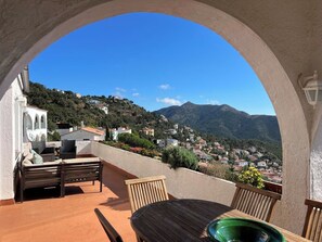 Une terrasse offrant une vue sur une ville perchée sur une colline et sur les montagnes.