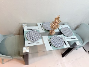 Una mesa de comedor puesta con platos, cubiertos y un centro de mesa decorativo.