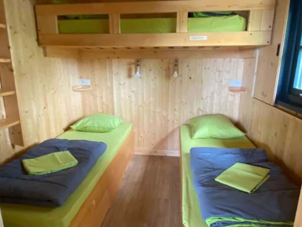 A room with two bunk beds, each with a pillow and a blanket.